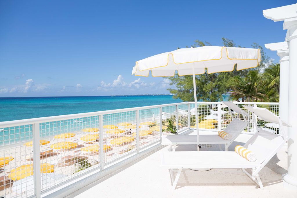 external terrace with white deckchairs overlooking beach at Palm Heights hotel Cayman Islands