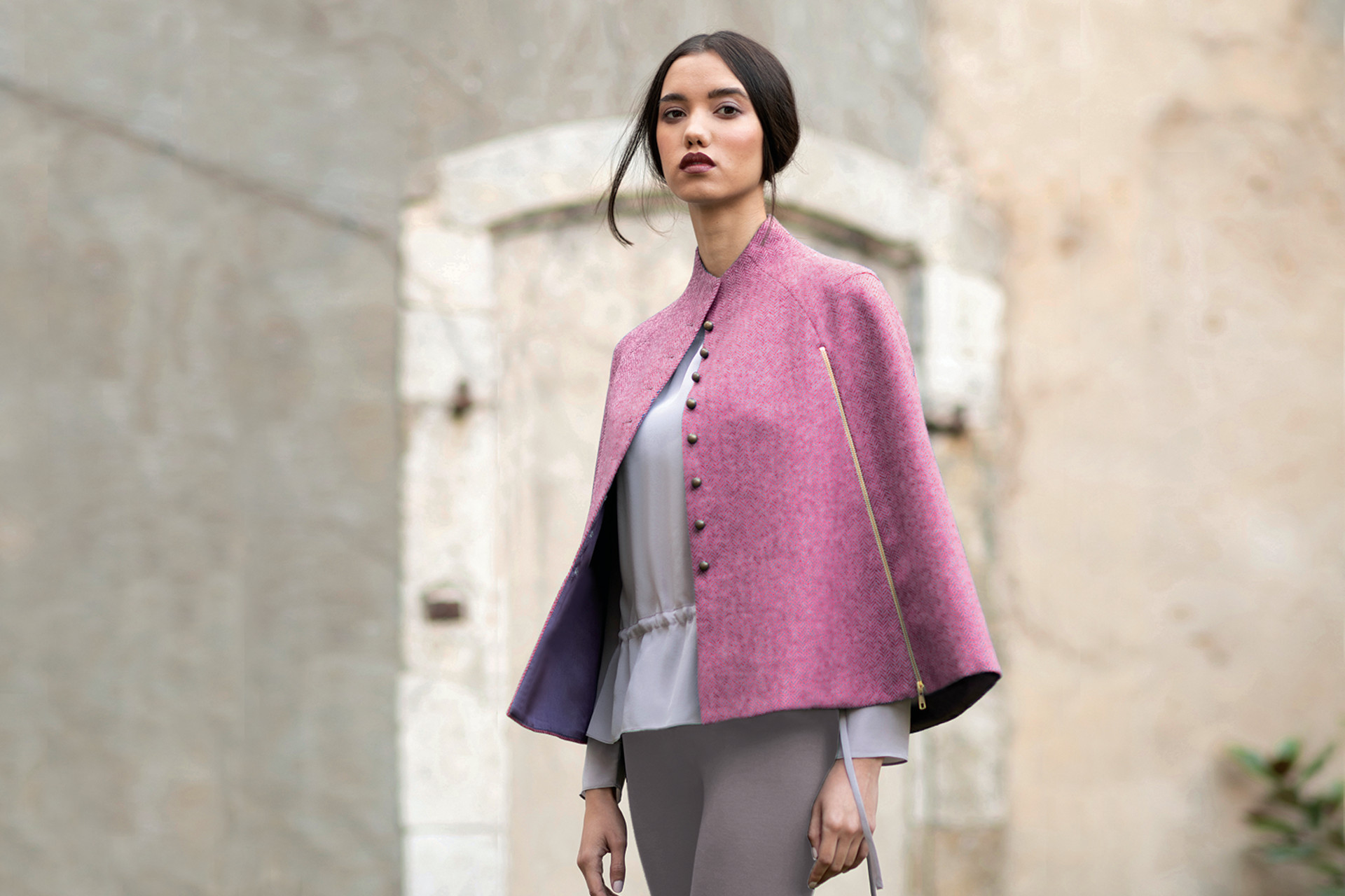 Model walking outdoors in a pink cape
