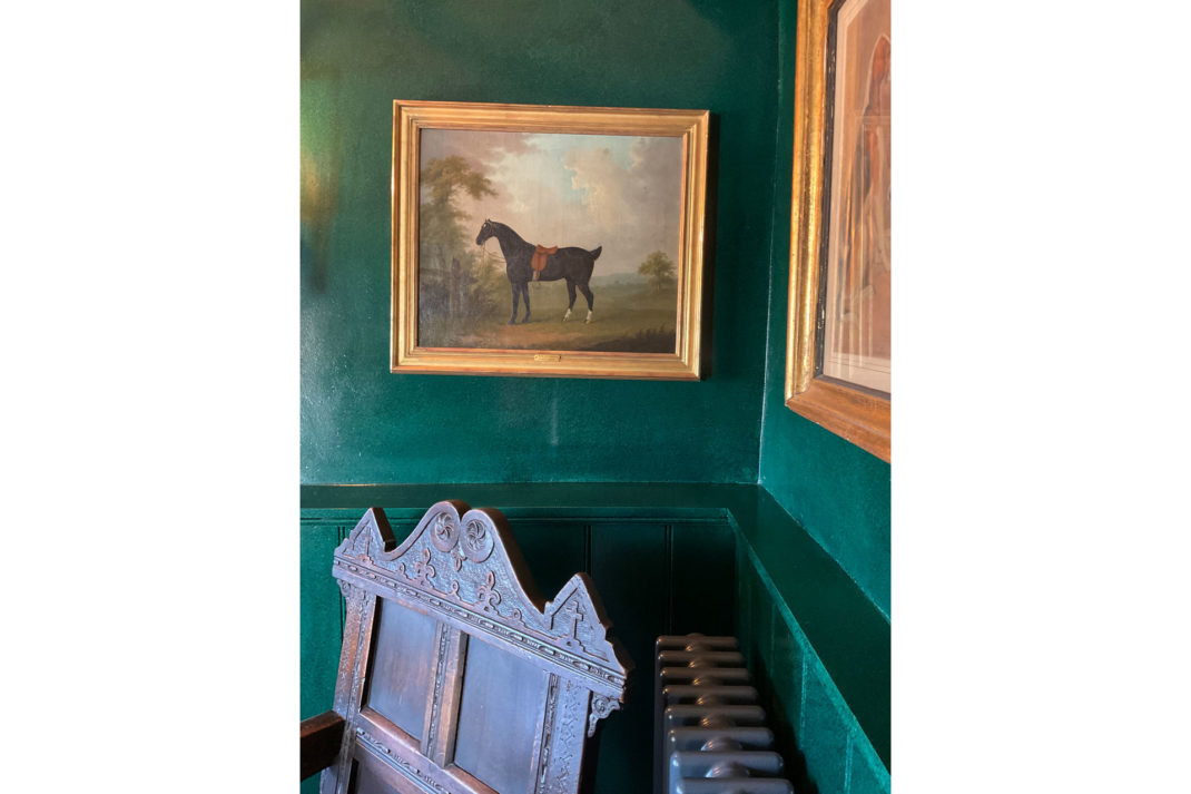 a close up of an antique equestrian painting behind a green wall at The Fox at Oddington
