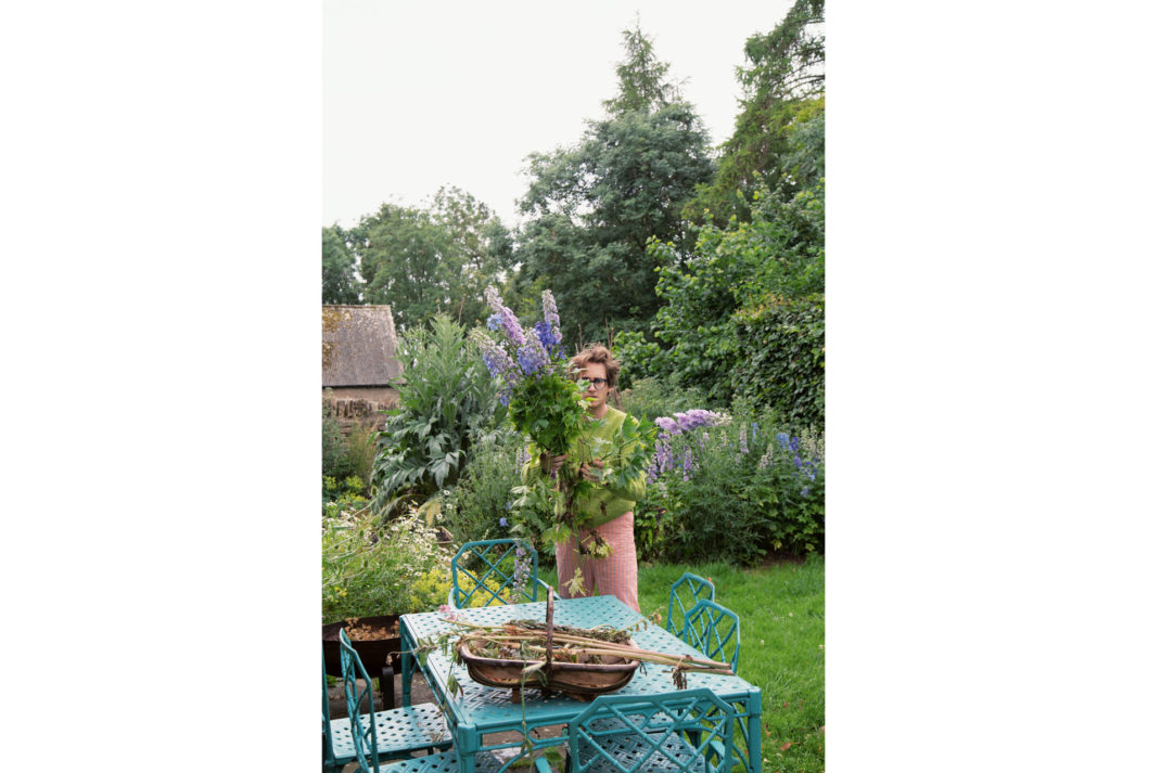 Interior designer and artist Luke Edward Hall holds a bouquet of cut flowers in his garden