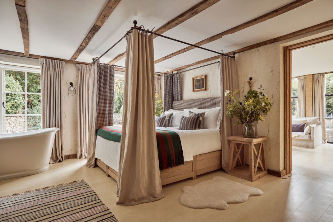 a canopy bed with gingham print curtains features in The Den Bedroom at the Cotswold's latest hotel, The Fox at Oddington
