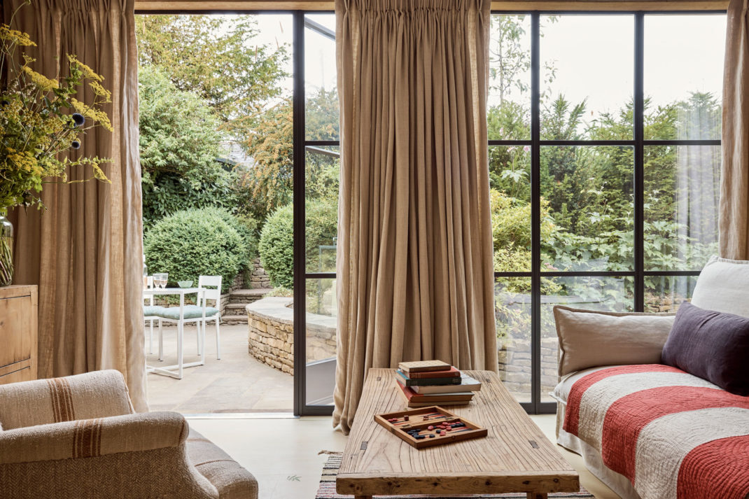 The living space of The Den, featuring a glass floor to ceiling wall that looks onto a private terrace.