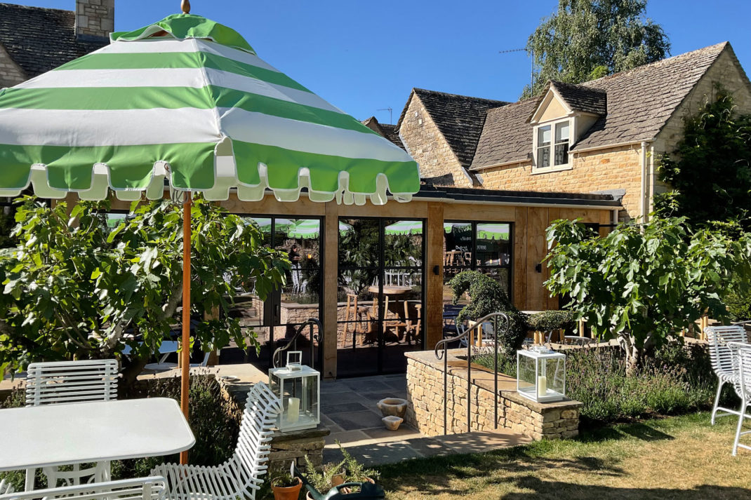 Green and white stripey parasols feature in the pub garden of The Fox at Oddington