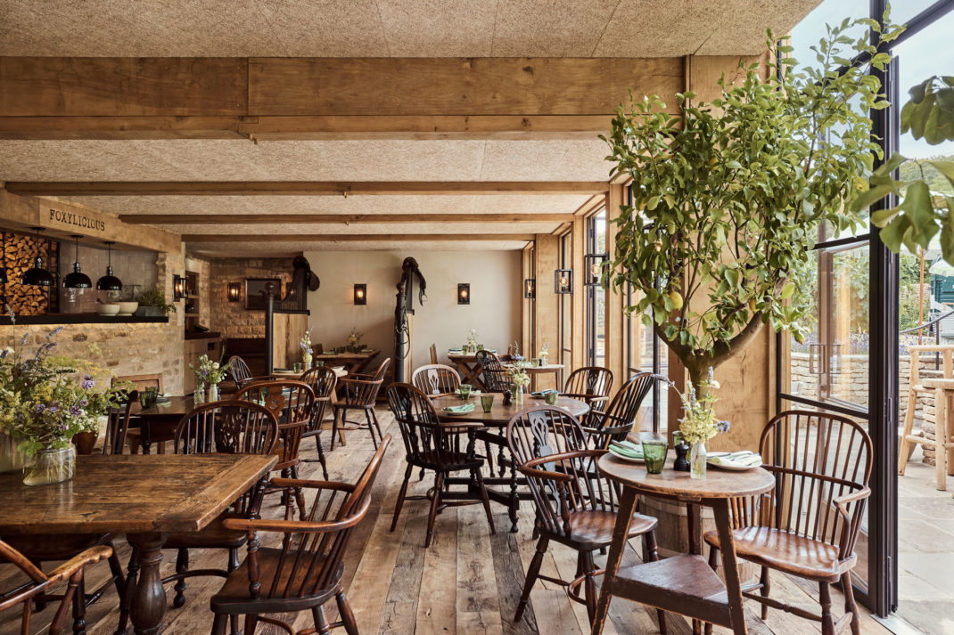 The Saddle Room restaurant at The Fox which has floor to ceiling glass windows, and mis matched wooden furniture