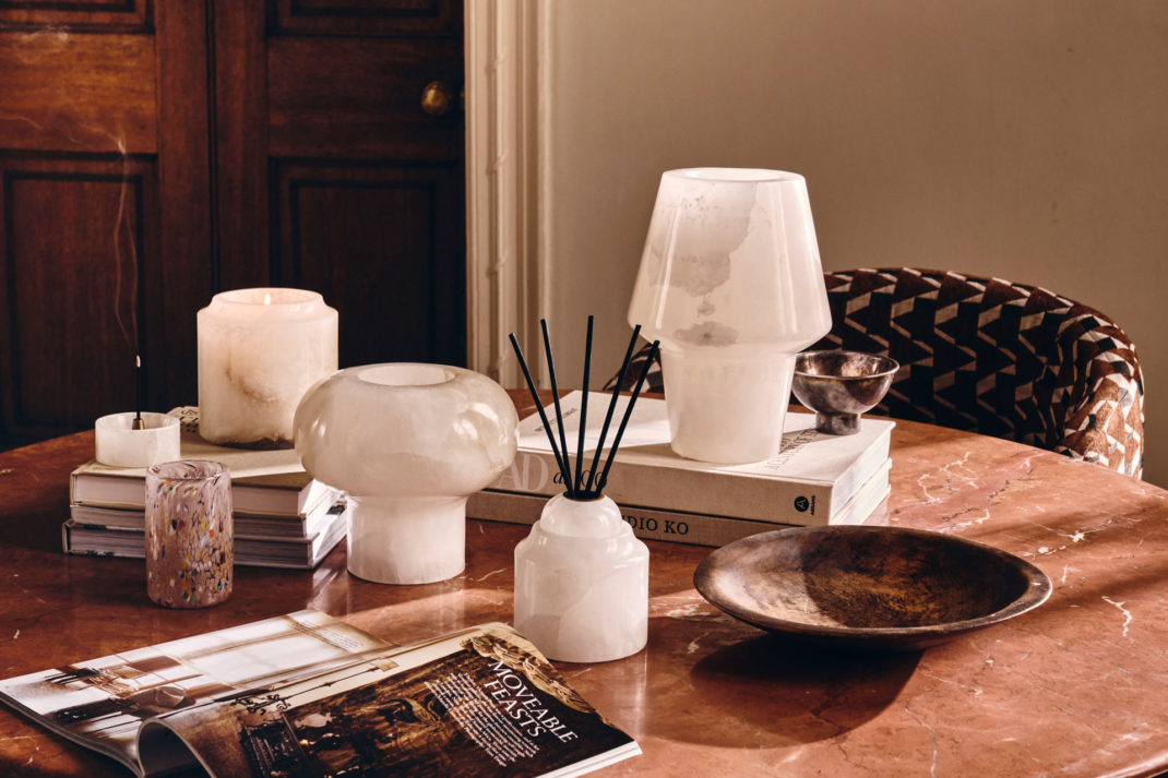an arrangement of candles, lamps, and diffusers by Soho Home, on a coffee table