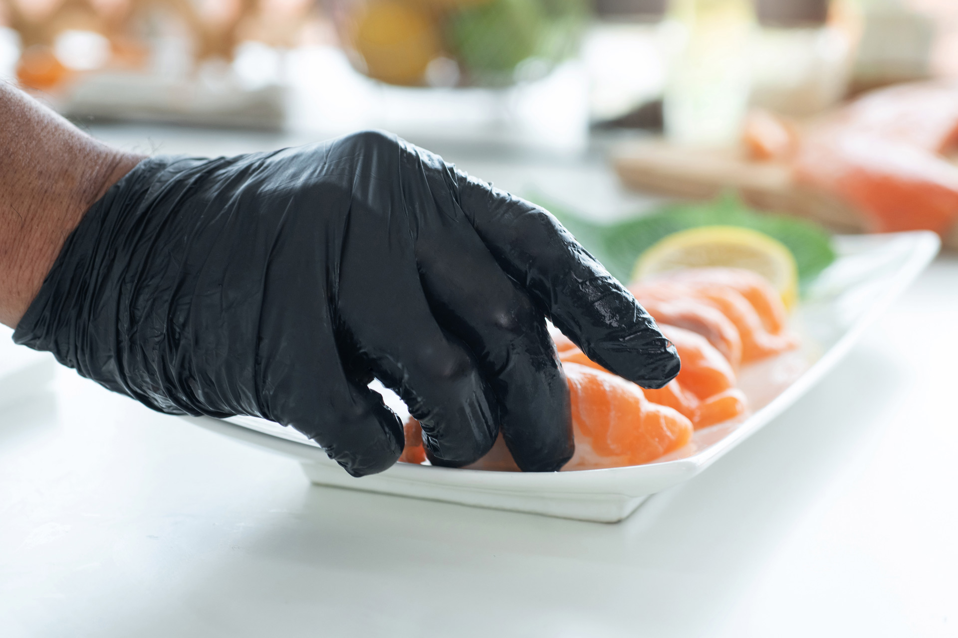 A hand with a black glove picking up some salmon