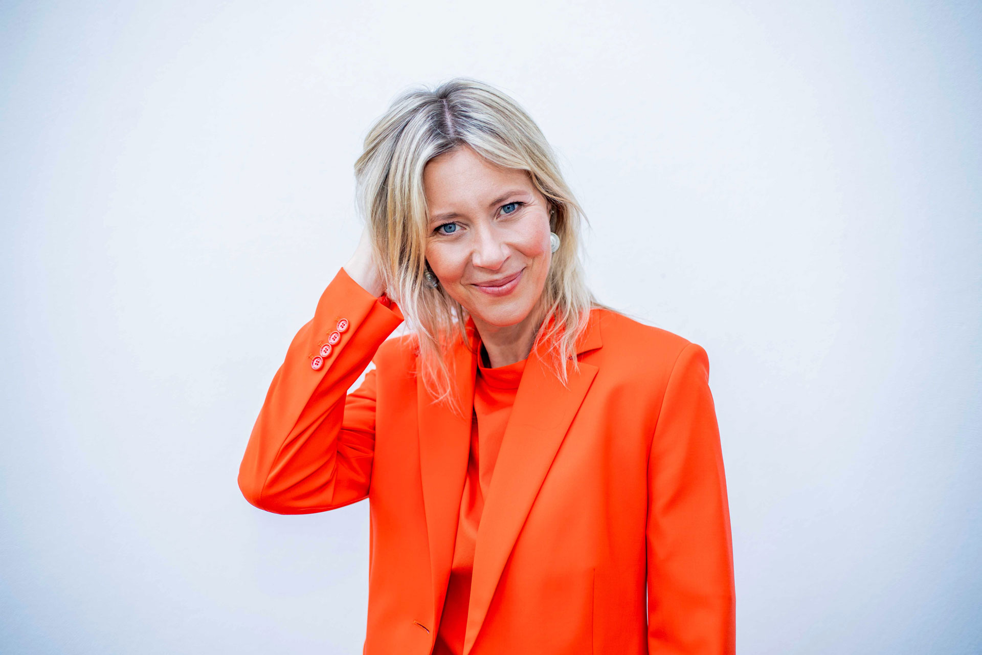 Rebekah Brown wearing a bright orange blazer