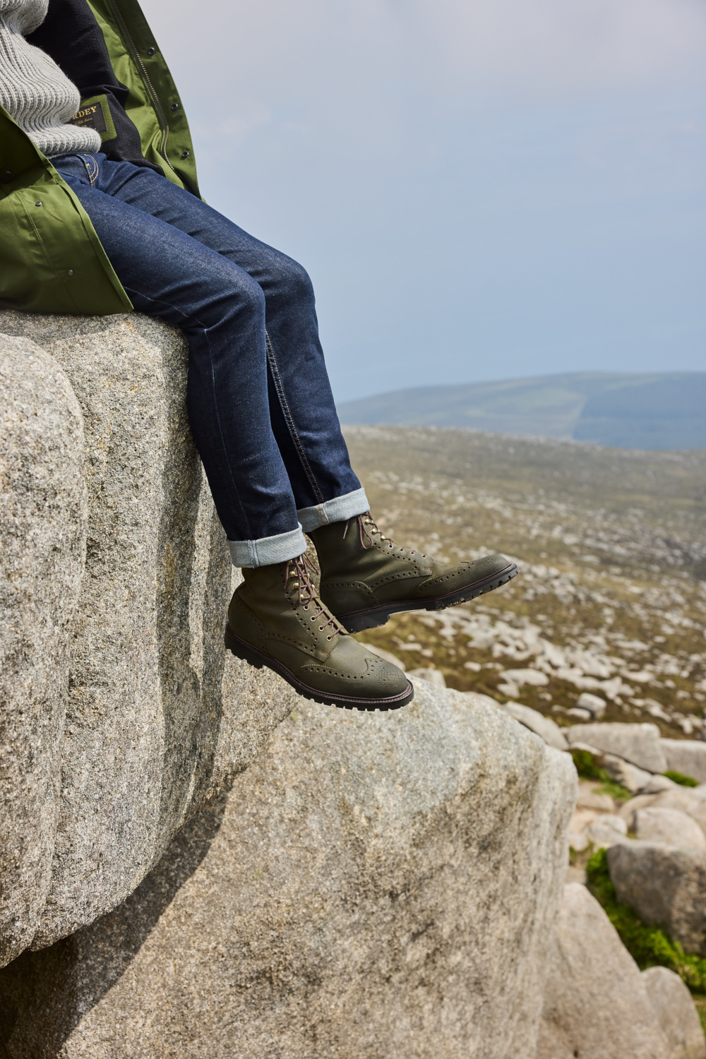 Close up of someone sitting on rock with legs hanging down