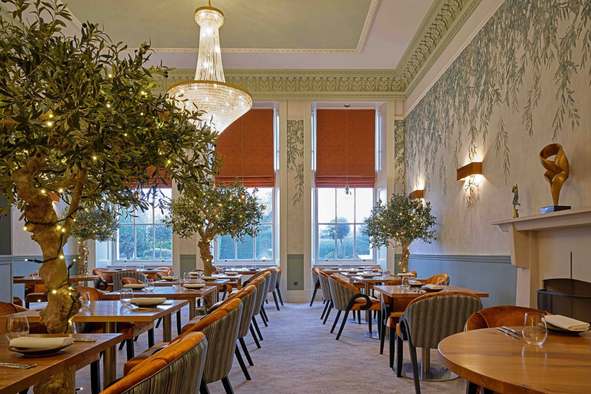 Dining room with chandelier, orange armchairs and olive trees
