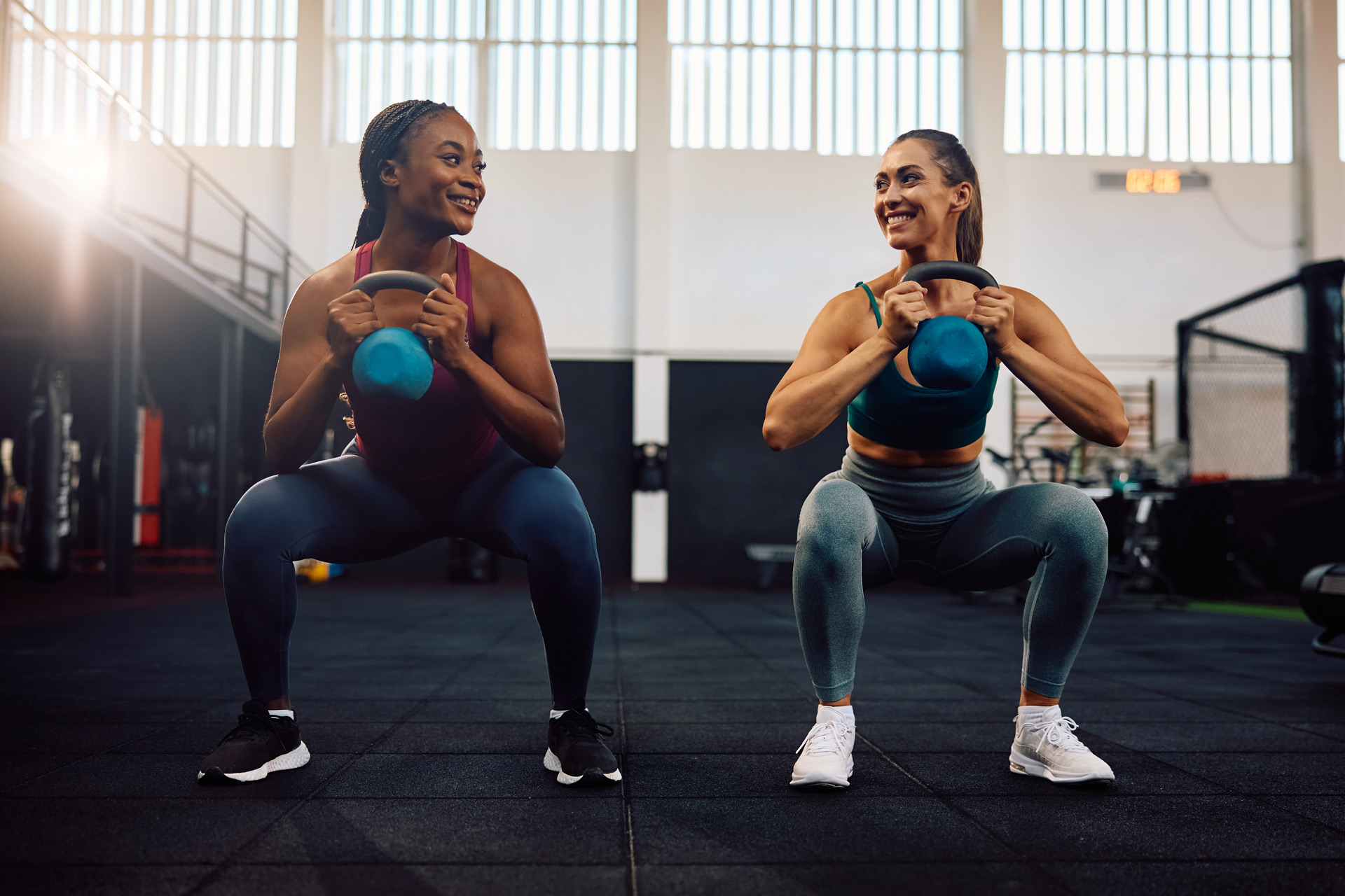 Two women doing a squat at the gym
