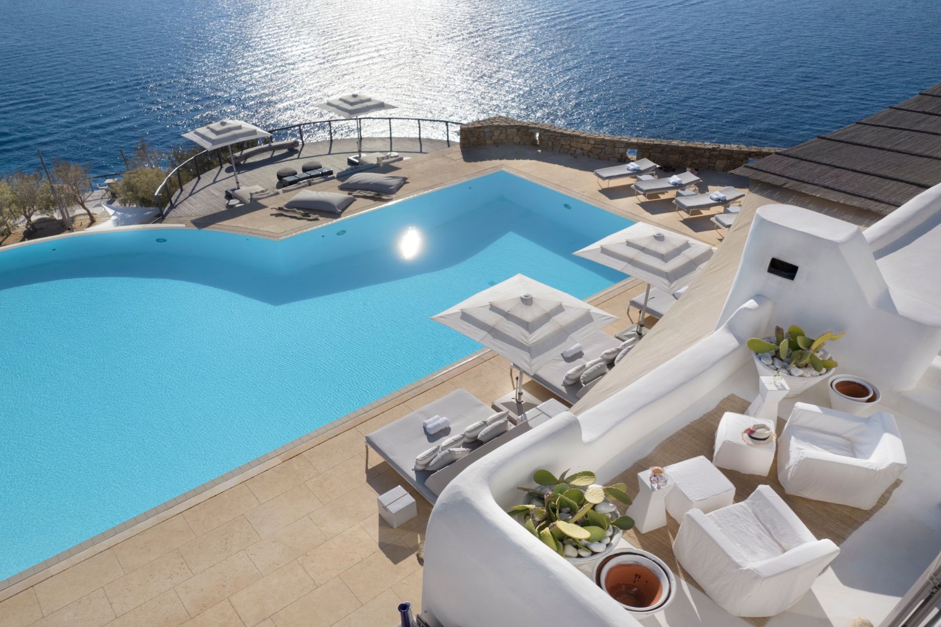Aerial view of infinity pool with white outdoor furniture