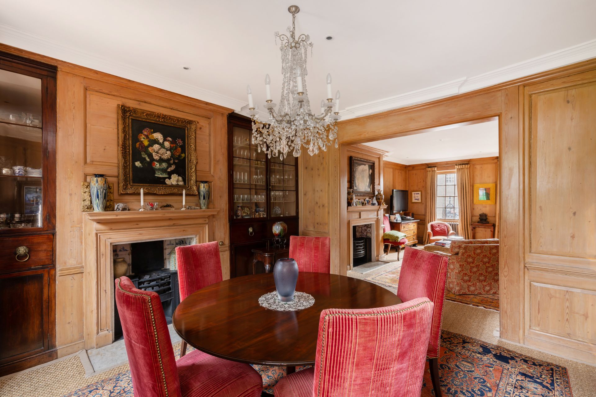 Wood panelled dining room with red velvet chairs, a fireplace and a chandelier